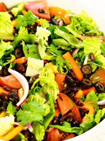 Big green salad in a white bowl with plenty of crunchy fresh ingredients.