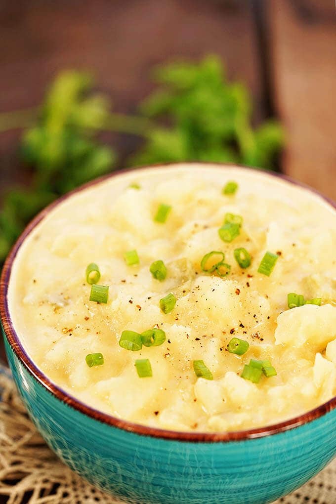 Easy creamy potato soup in a blue bowl topped with minced chives.