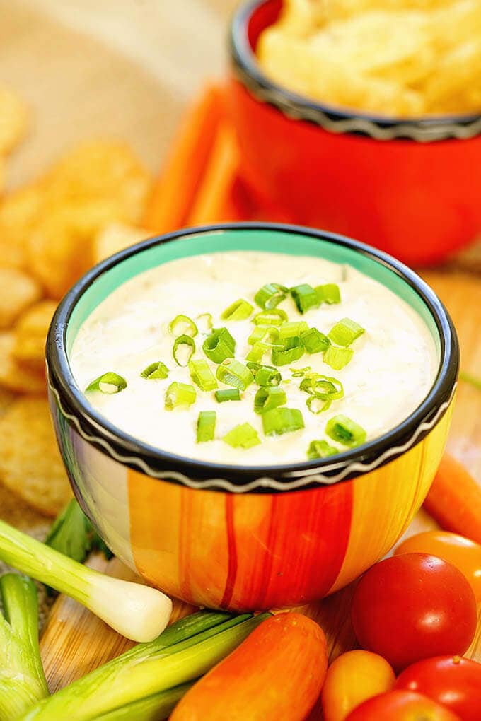 Green Onion Dip Recipe surrounded by dippers like potato chips, cherry tomatoes, carrots and green onions.
