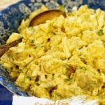 Deviled Egg Potato Salad in a blue bowl with a serving spoon