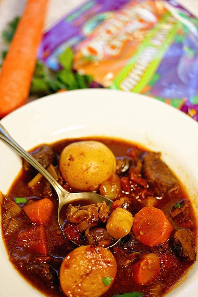 Lamb Stew in a white bowl surrounded with figs and carrots.