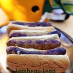 Beer Brat Recipe - four grilled brats in buns on a platter with a Green Bay Packer Helmet in the background.