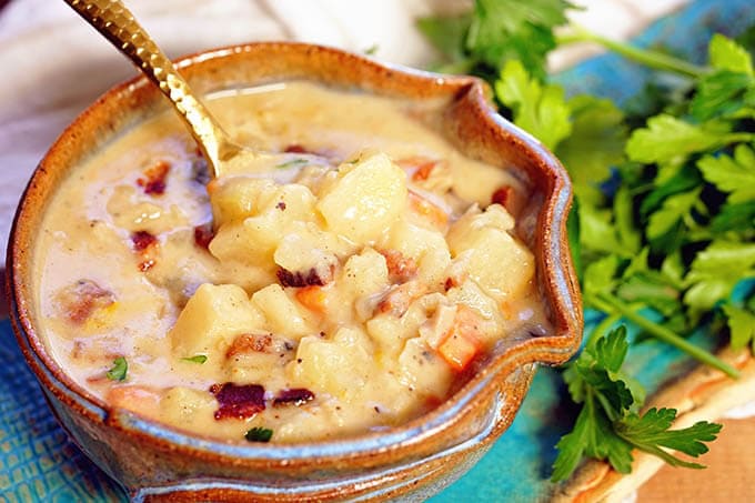 A blue bowl filled with the Boston clam chowder topped with crumbled bacon.