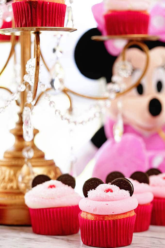 Minnie Mouse cupcakes surrounding a cake stand and stuffed Minnie Mouse!