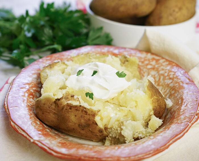 Potato in bowl topped with sour cream. 