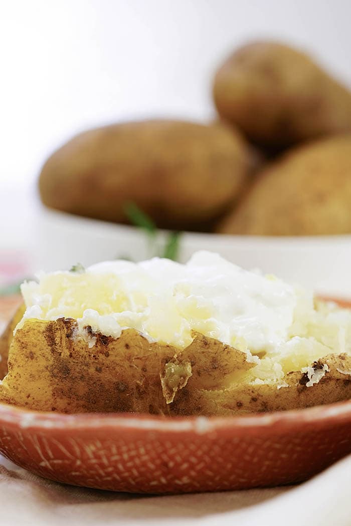 Pressure cooker baked potatoes topped with butter and sour cream.