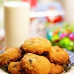 A plate filled with white chocolate macadamia nut cookies with a glass of milk