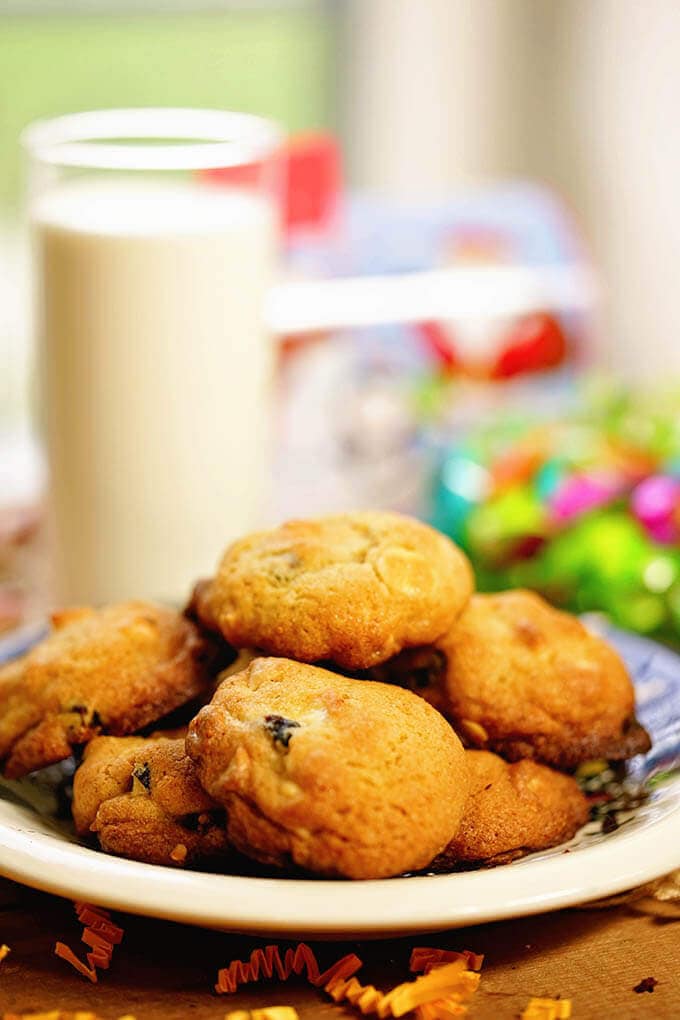 A plate filled with white chocolate macadamia nut cookies with a glass of milk