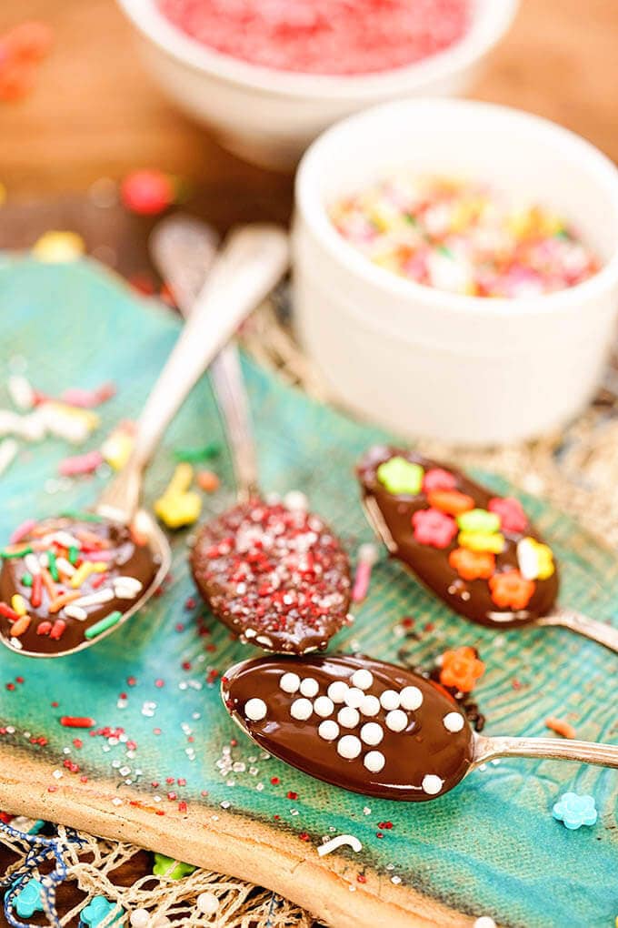 Four Chocolate Spoons covered with sprinkles on a blue platter with