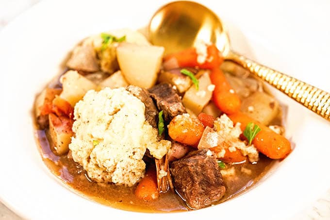 Easy Crockpot Beef Stew in a white bowl with spoon.