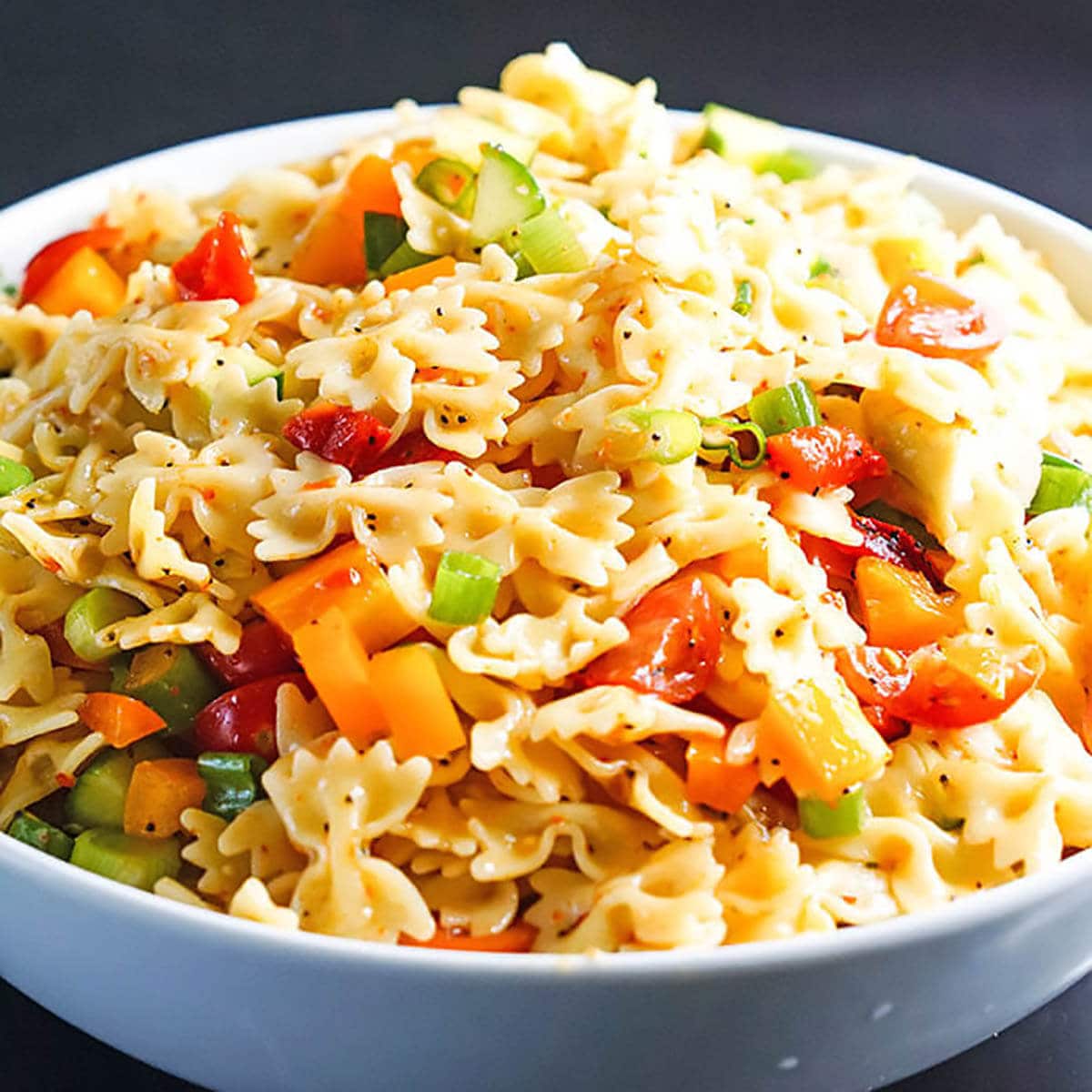 White bowl filled with Italian bow tie pasta salad.