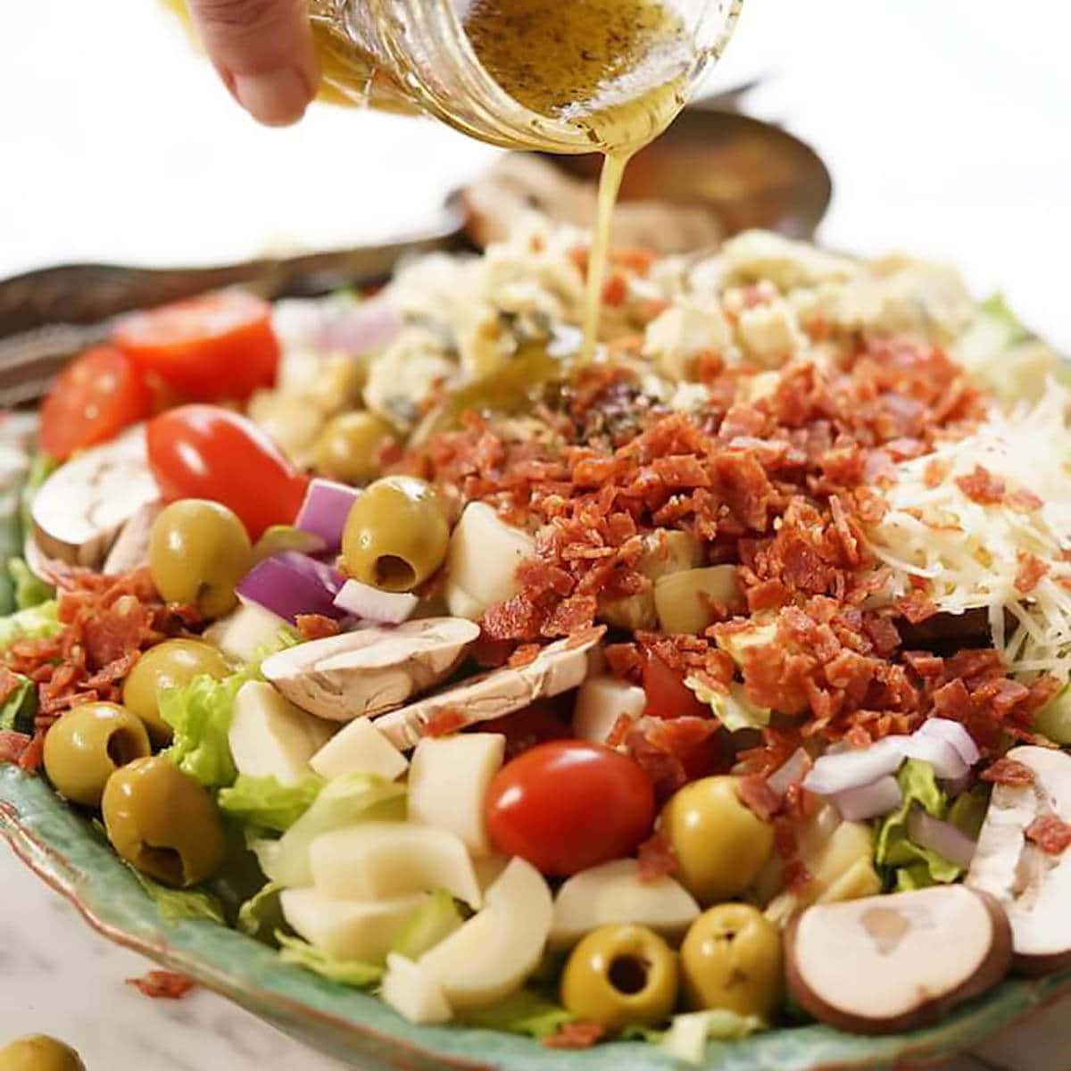 Steakhouse salad with vinaigrette pouring over it.