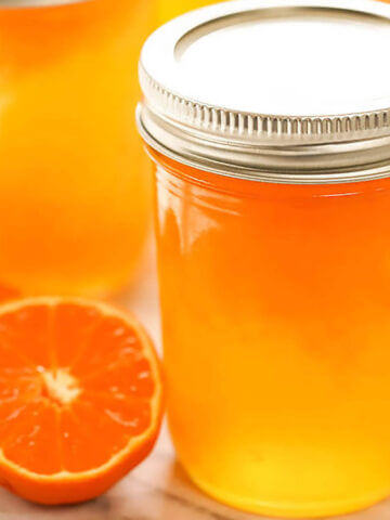 Orange Jelly in jar with sliced mandarin on the side.