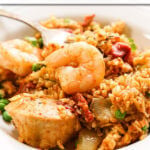 Slow Cooker Paella in white bowl with fork.