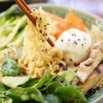 Ramen Noodle Recipe in bowl served with chopsticks, topped with a soft boiled egg.