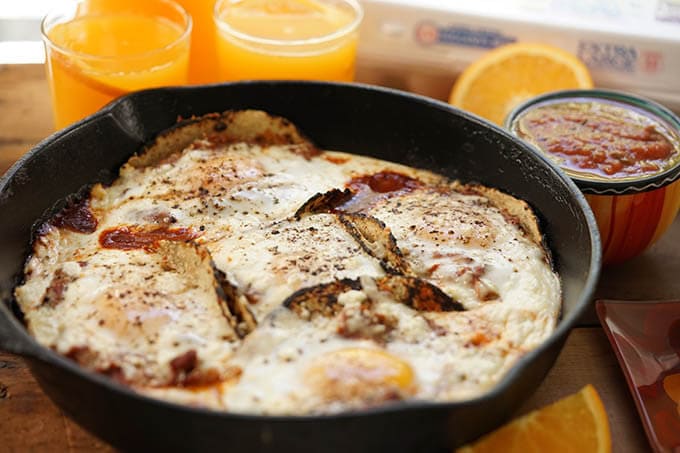 Easy Huevos Rancheros Recipe served with orange juice and a bowl of salsa.