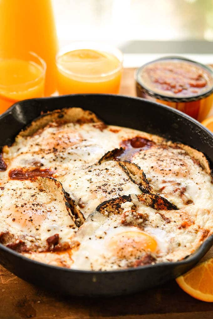 A cast iron skillet filled with Huevos Rancheros recipe serve with fresh squeezed orange juice.