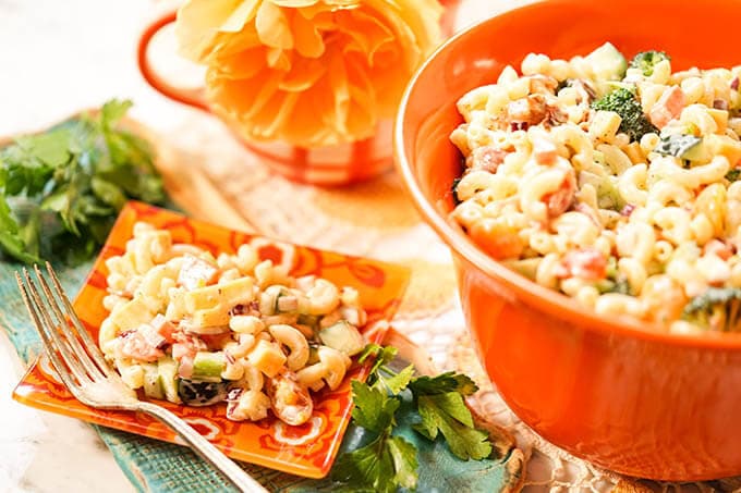 Macaroni Pasta Salad Recipe in orange bowl with a serving on a plate with fork.