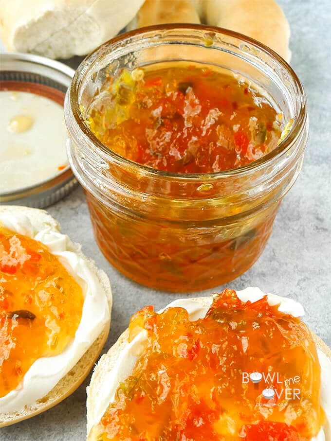 Bagel slices with cream cheese topped with Pepper Jam with jar of jam.