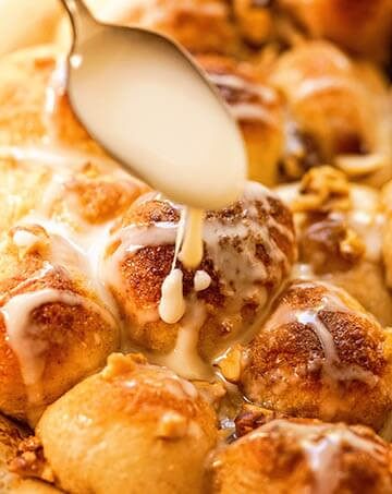 Pull Apart Cinnamon Rolls being topped with a sweet glaze.