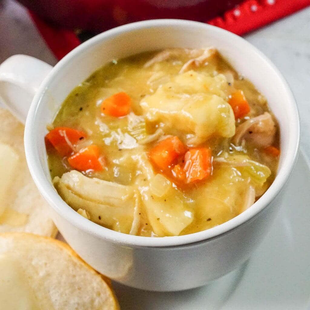 Easy Chicken and Dumpling Soup in white bowl with biscuits.