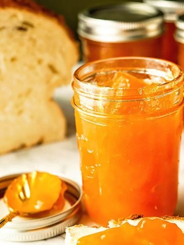 Jars of apricot jam spread on fresh bread.