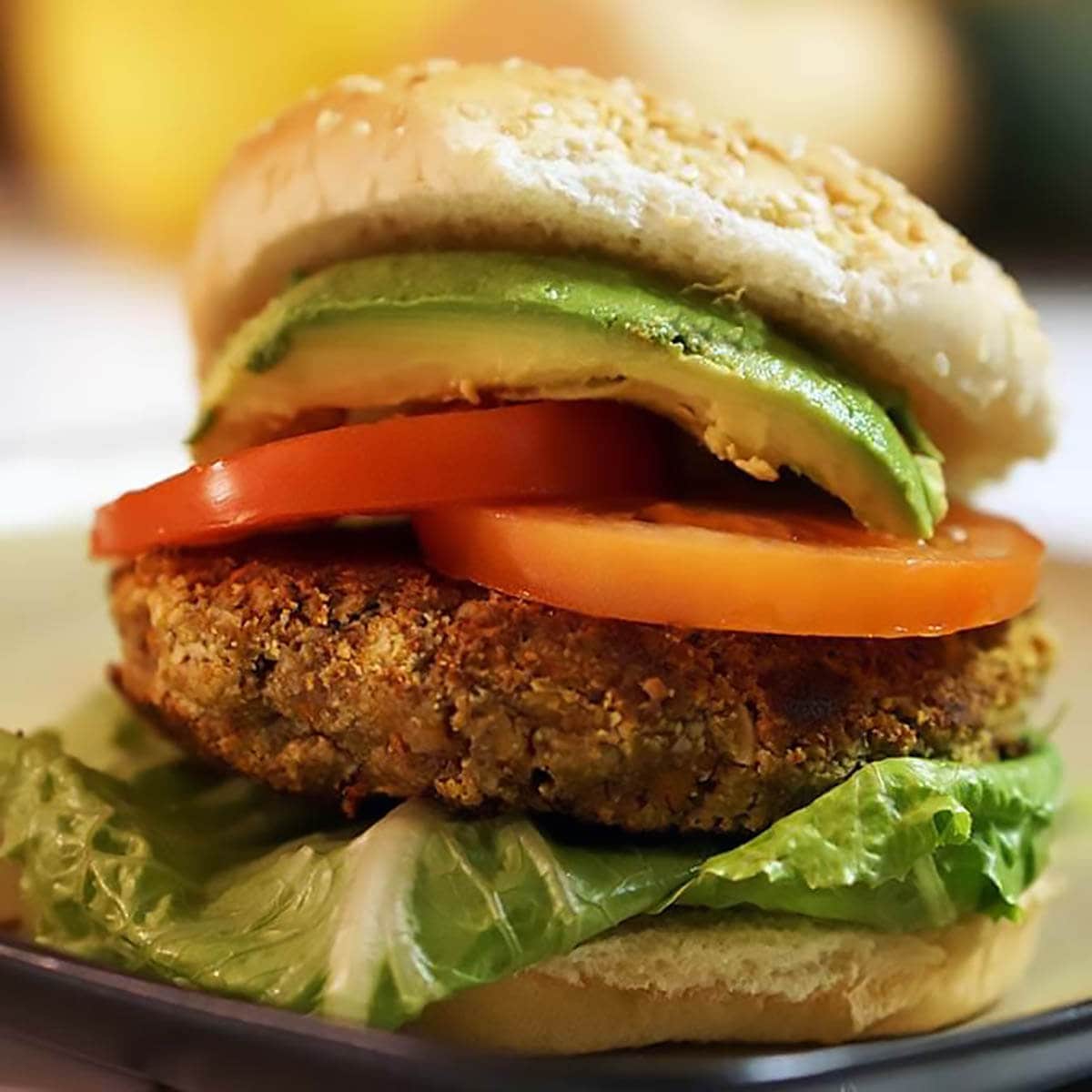 Burger on bun topped with lettuce, diced tomatoes and avocado.