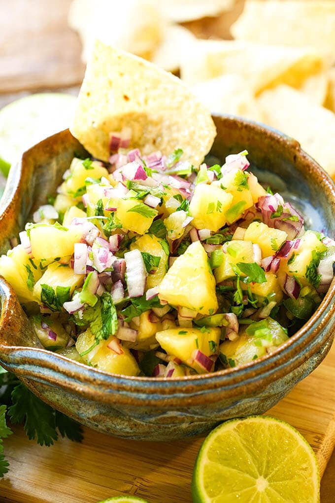 Pineapple Salsa in blue bowl with chips and sliced lime