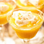 Lemon curd in dessert glass topped with whipped cream.