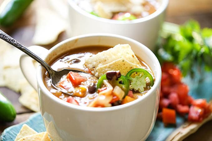 Creamy chicken enchilada soup in white bowl with spoon.