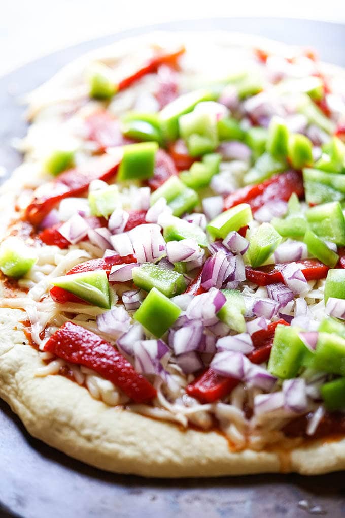 Pizza dough topped with sauce, cheese onions and bell pepper. 