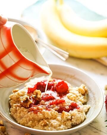 Oatmeal in bowl with strawberries topped off with milk