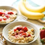 Instant Pot Steel Cut Oats in bowls topped with strawberries and nuts.
