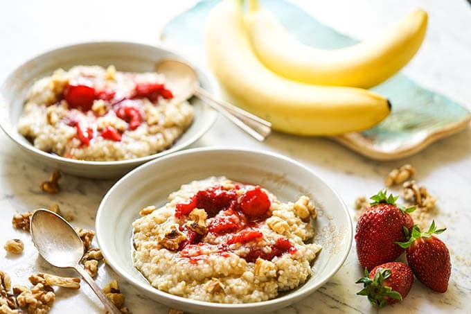 Instant Pot Steel Cut Oats in bowls topped with strawberries and nuts.