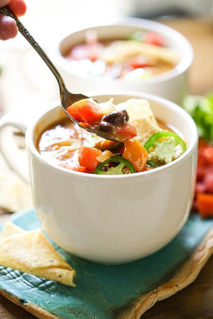 Bowls of slow cooker enchiladas soup with spoon