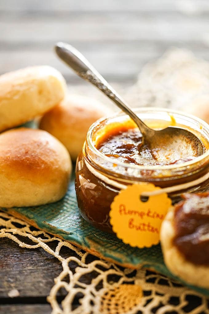 Pumpkin butter in jar with rolls.