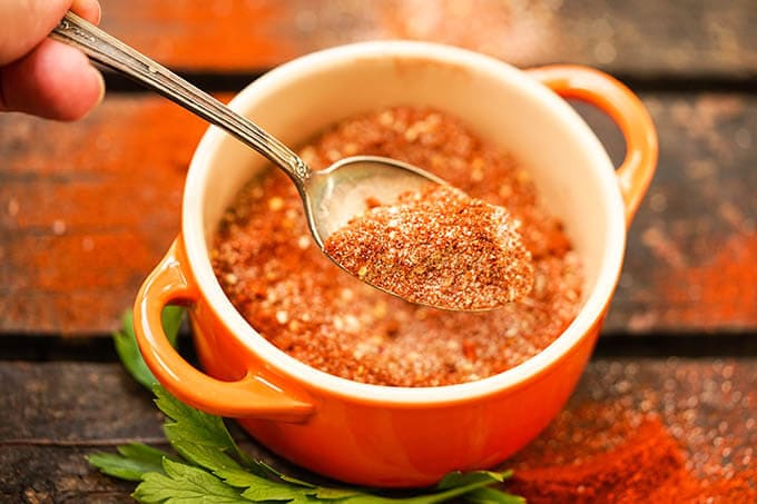 Dry spice mix in orange jar with spoon.