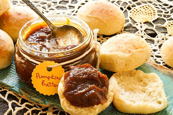 Pumpkin butter and rolls on blue platter.