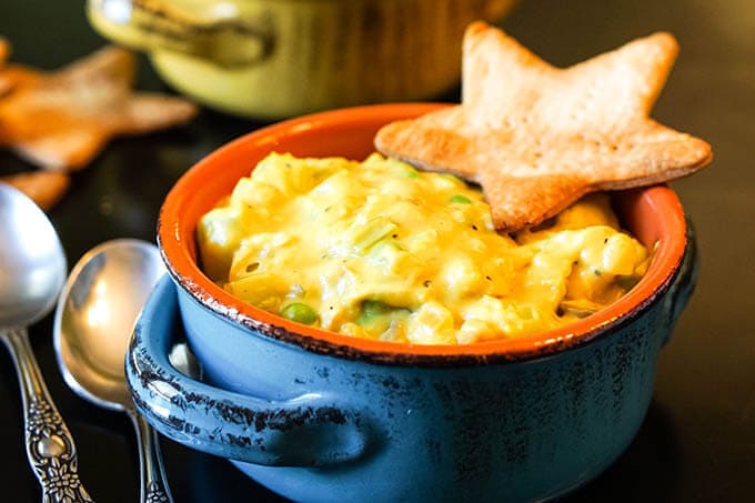 Blue bowl filled with soup topped with cracker.