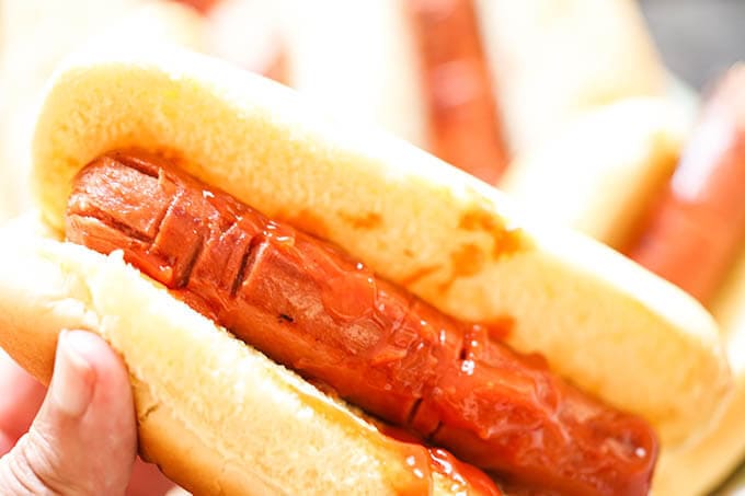 Close of up of Hot dog carved to look like fingers in bun with ketchup .