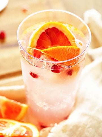 Tall glass filled with Paloma cocktail and garnished with a slice of pink grapefruit.