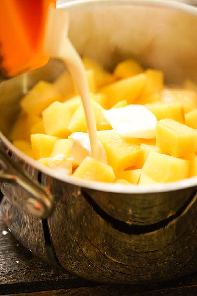 Cream being added to a pot with cooked vegetables. 