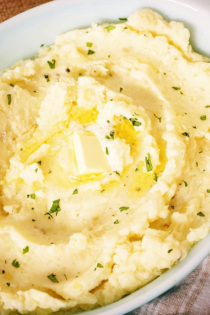A dish filled with creamy mashed potatoes with melting butter