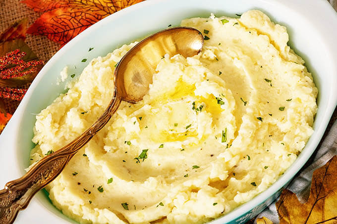 Casserole dish filled with mashed potatoes with serving spoon.