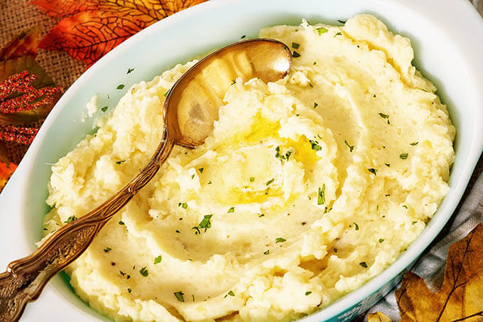 Casserole dish filled with potatoes with a butter melting in the center.