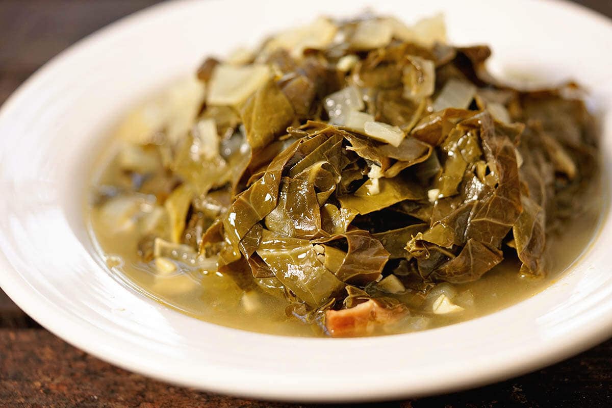 Leftover ham and collard greens in white bowl.