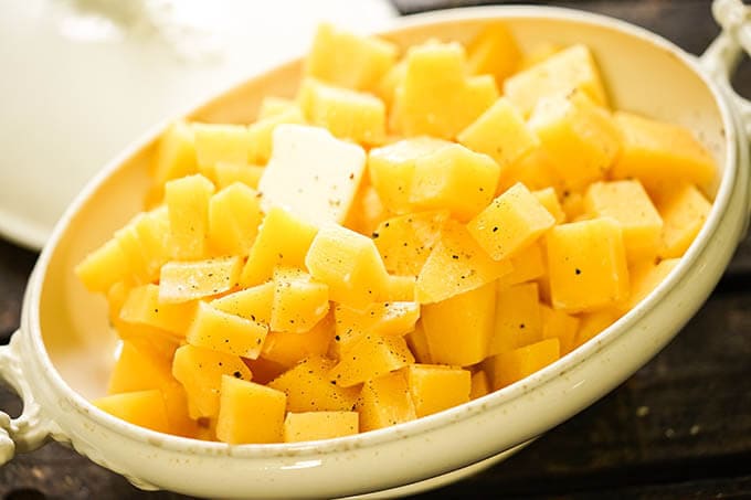 Buttery Rutabagas in white casserole dish topped with butter.