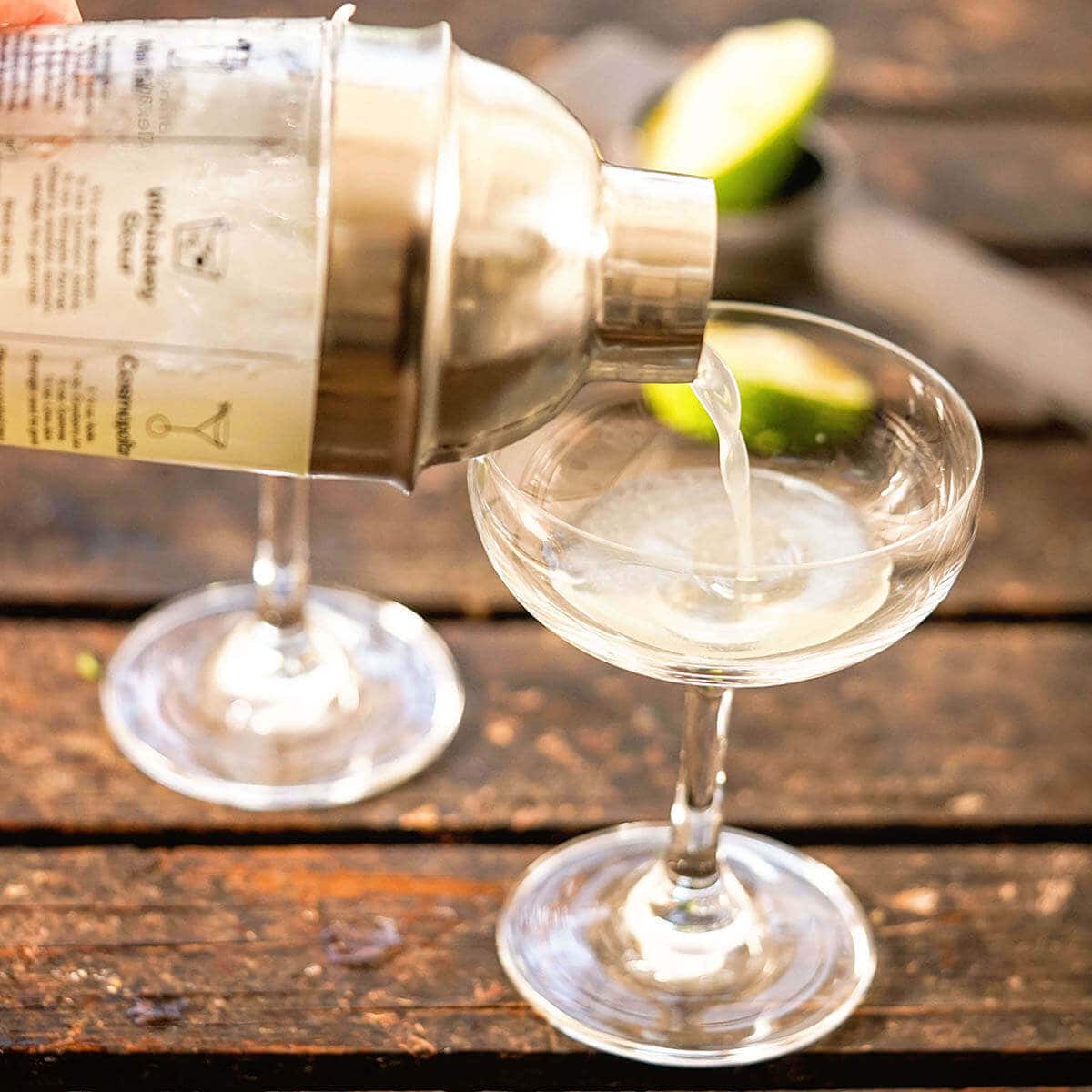 Cocktail shaker pouring a drink into a glass.