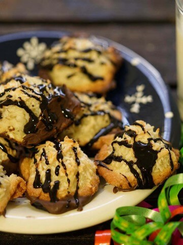 Coconut Macaroons with chocolate drizzle on plate with a glass of milk.