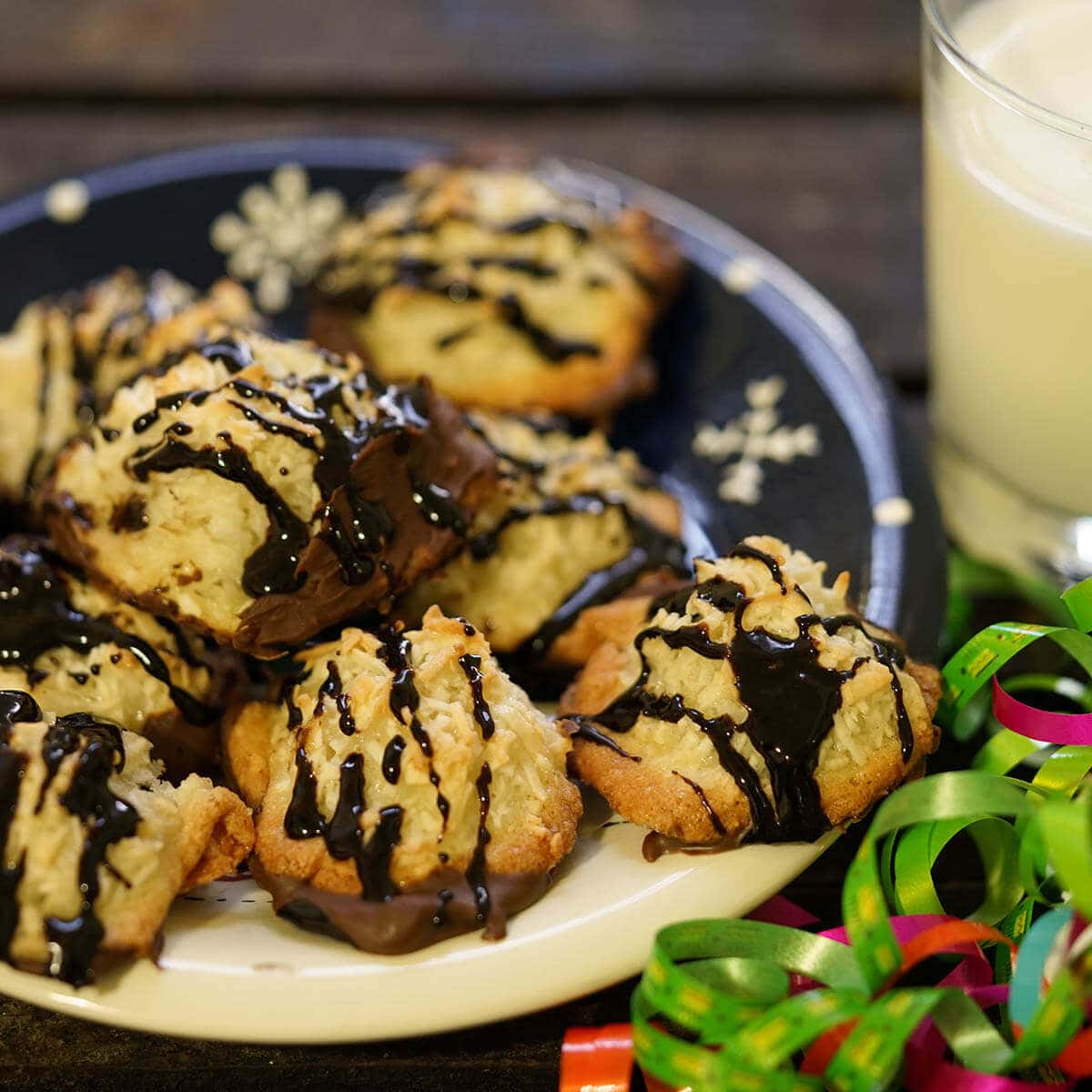 Coconut Macaroons with chocolate drizzle on plate with a glass of milk.